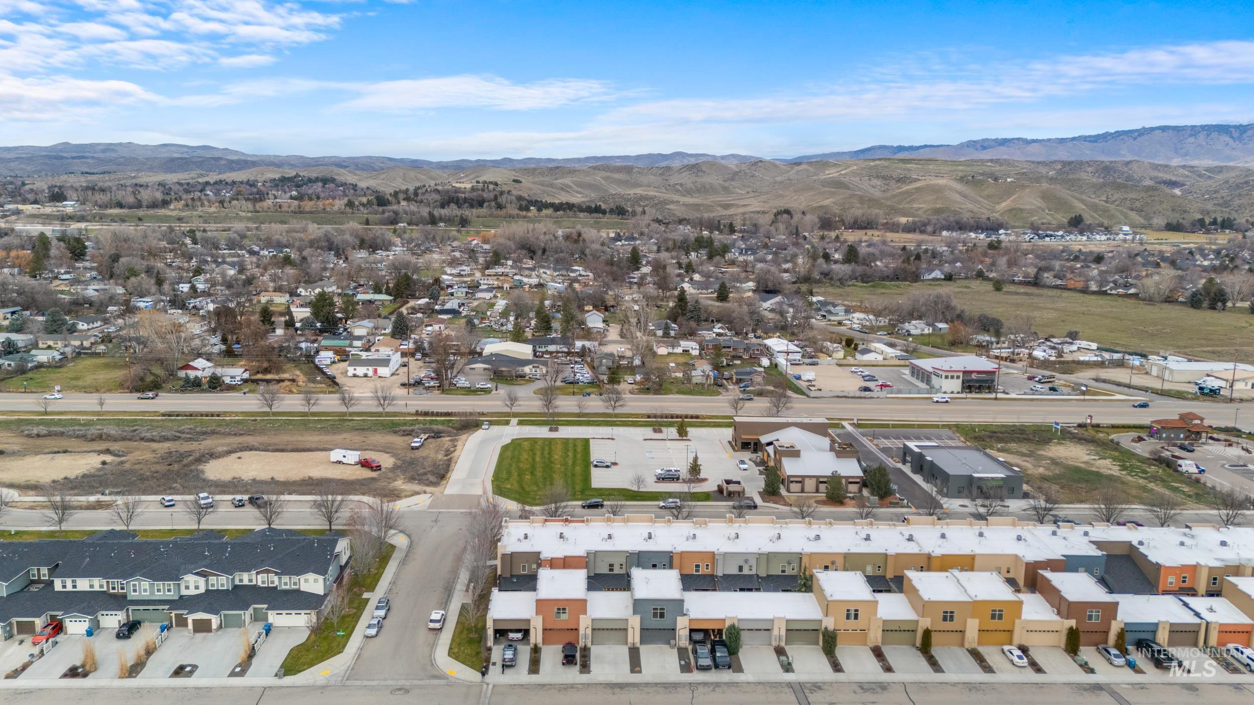 Aerial overview of property's location with a mountainous background and nearby suburban area