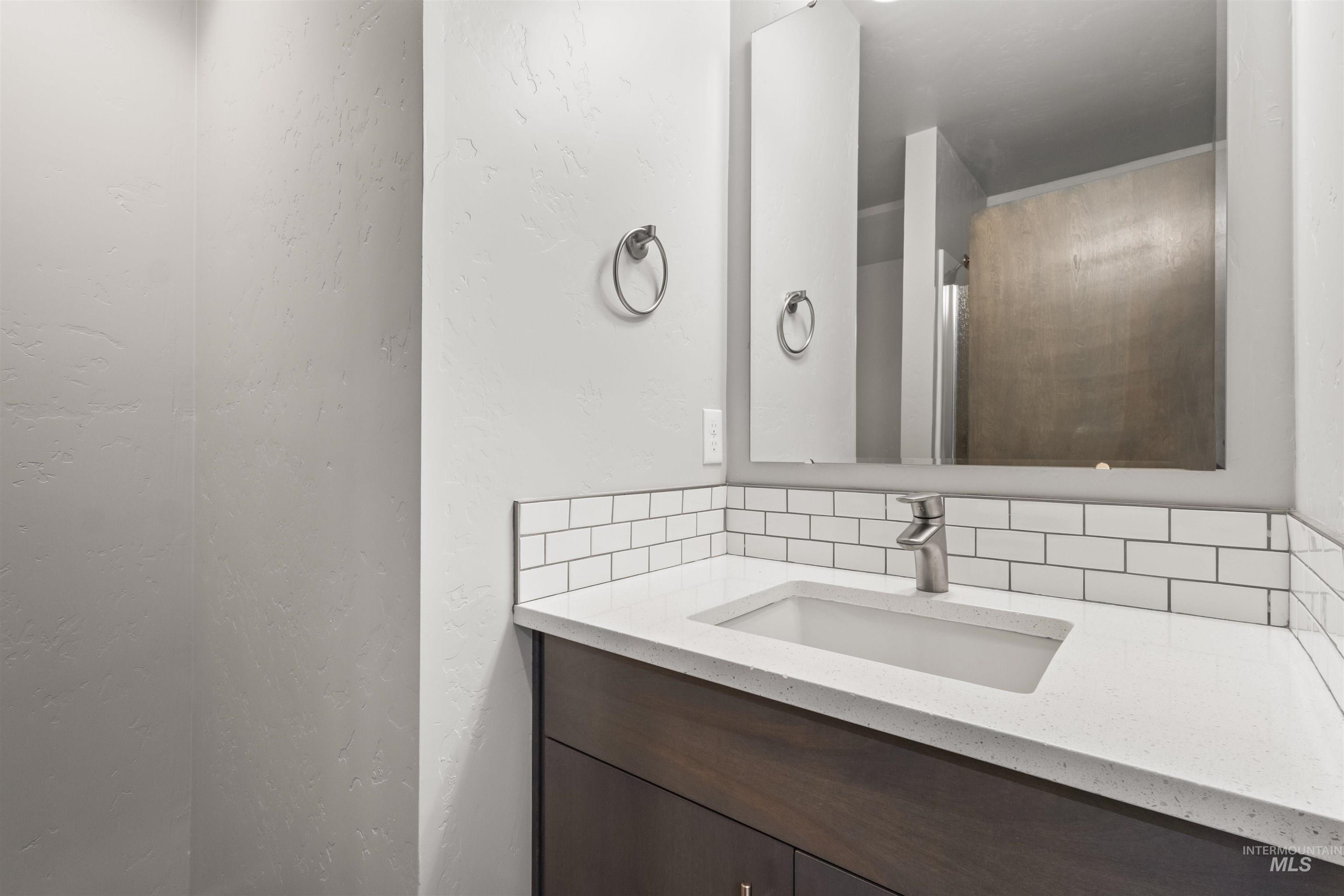 Bathroom on main floor with tasteful backsplash, vanity,  shower stall