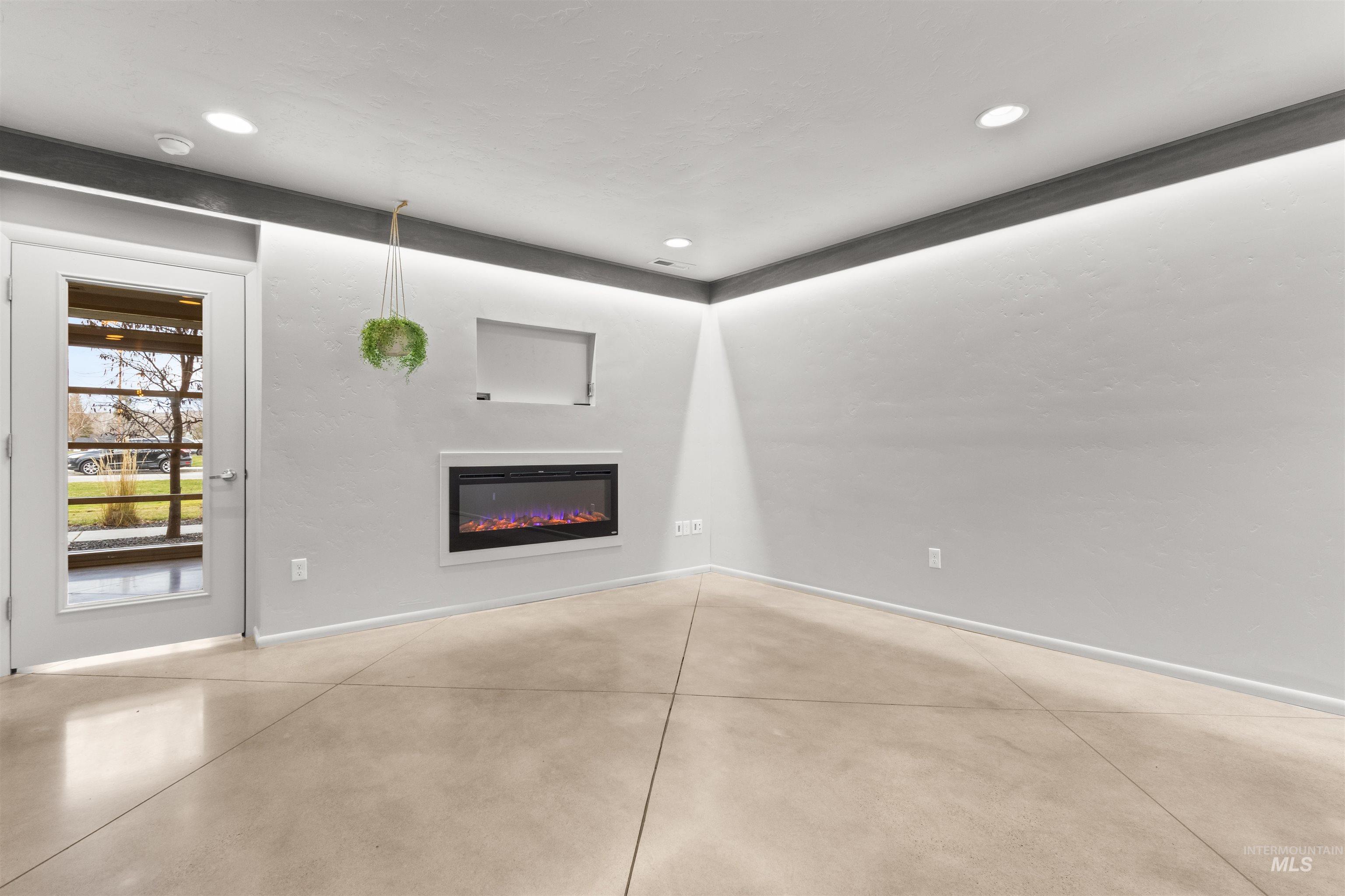 Great room with a recessed glass covered fireplace, concrete floors, and recessed lighting