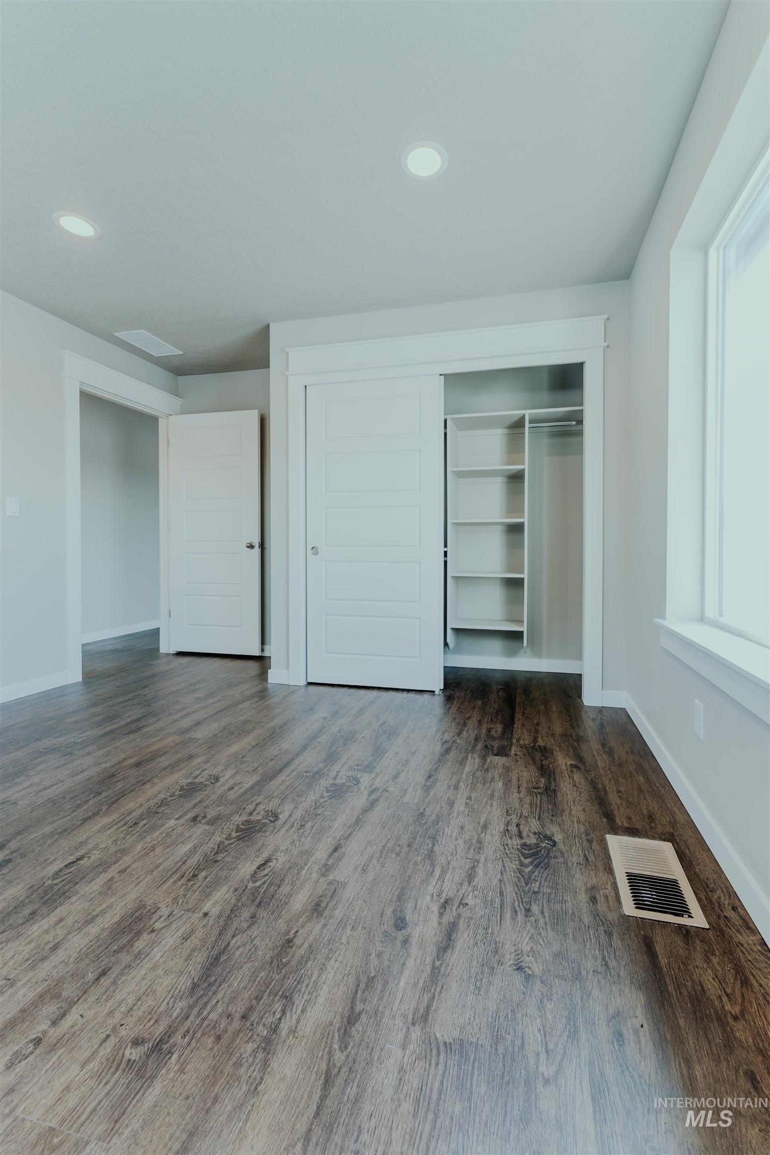 Unfurnished bedroom with dark wood-style floors, a closet, and recessed lighting