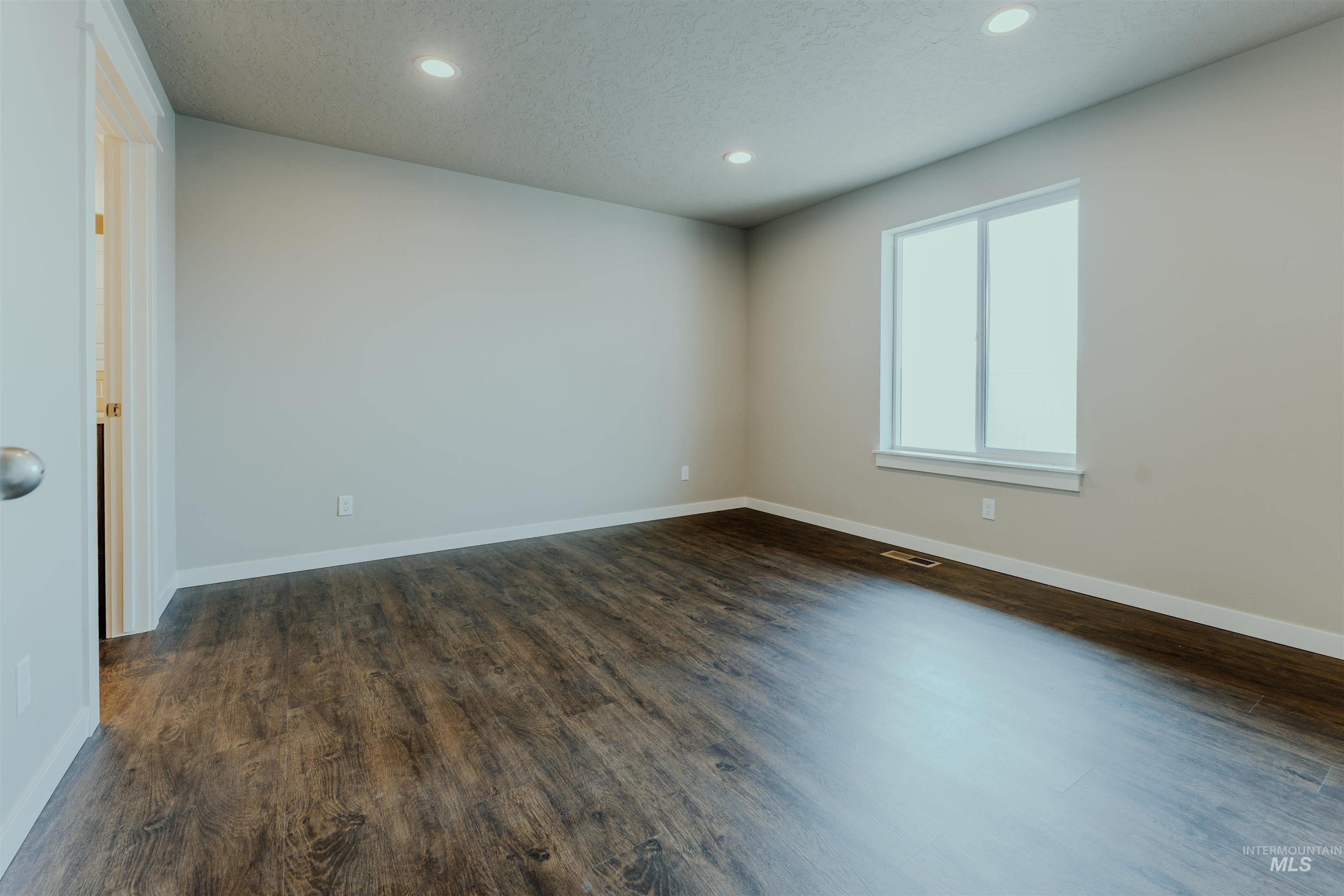 Unfurnished room featuring dark wood-style flooring, recessed lighting, and a textured ceiling