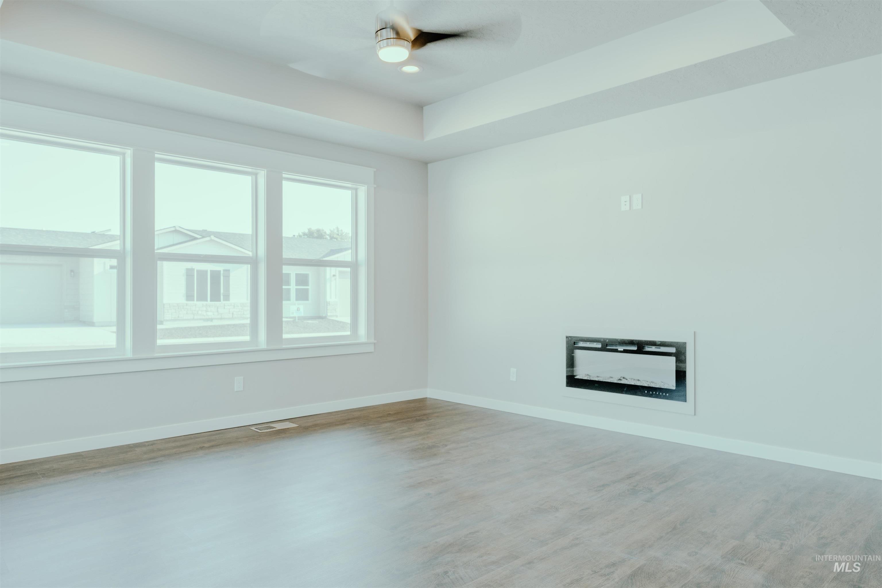 Unfurnished room with a tray ceiling, light wood-style flooring, and ceiling fan