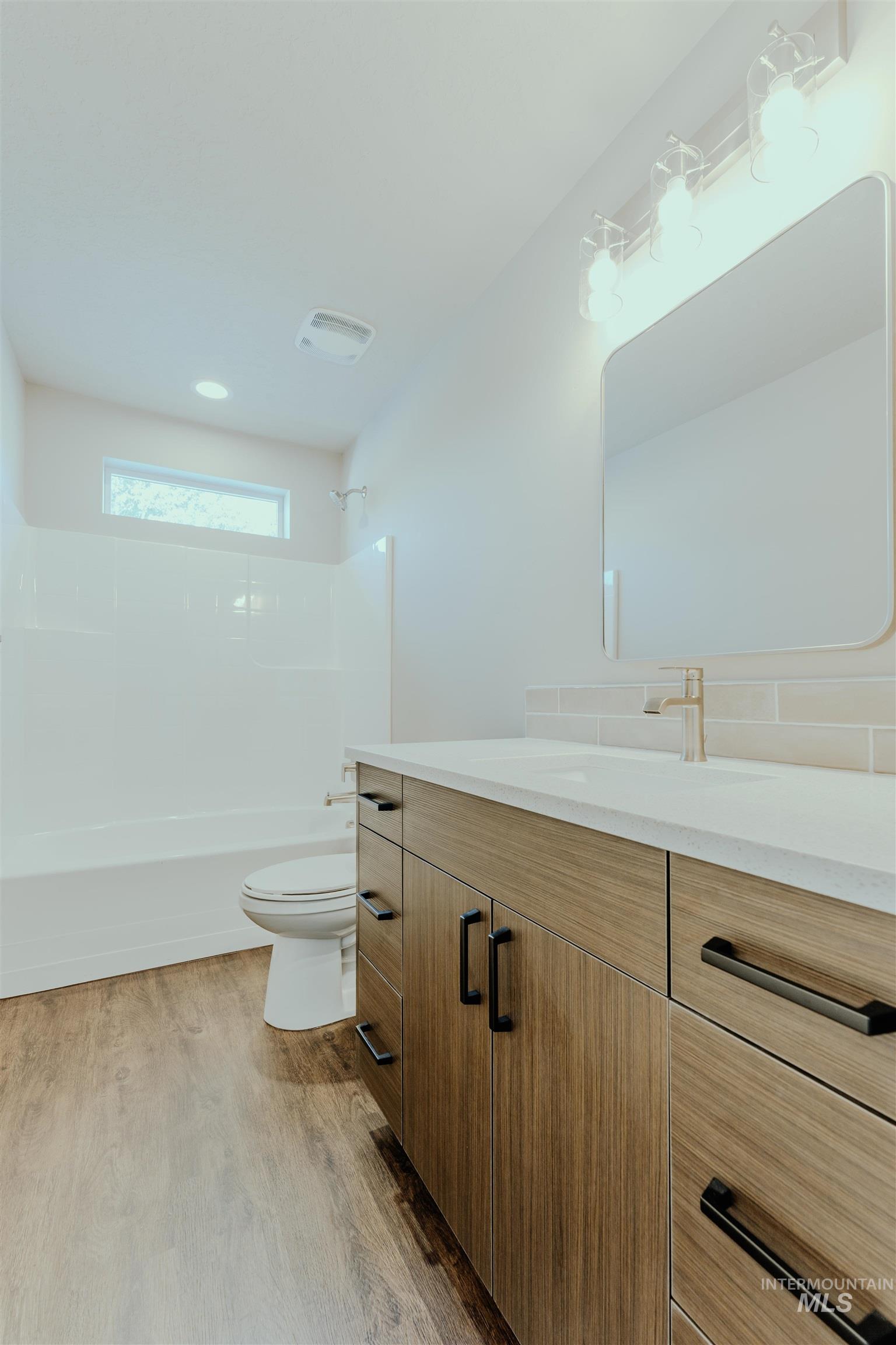 Bathroom with vanity, bathing tub / shower combination, and light wood-style floors