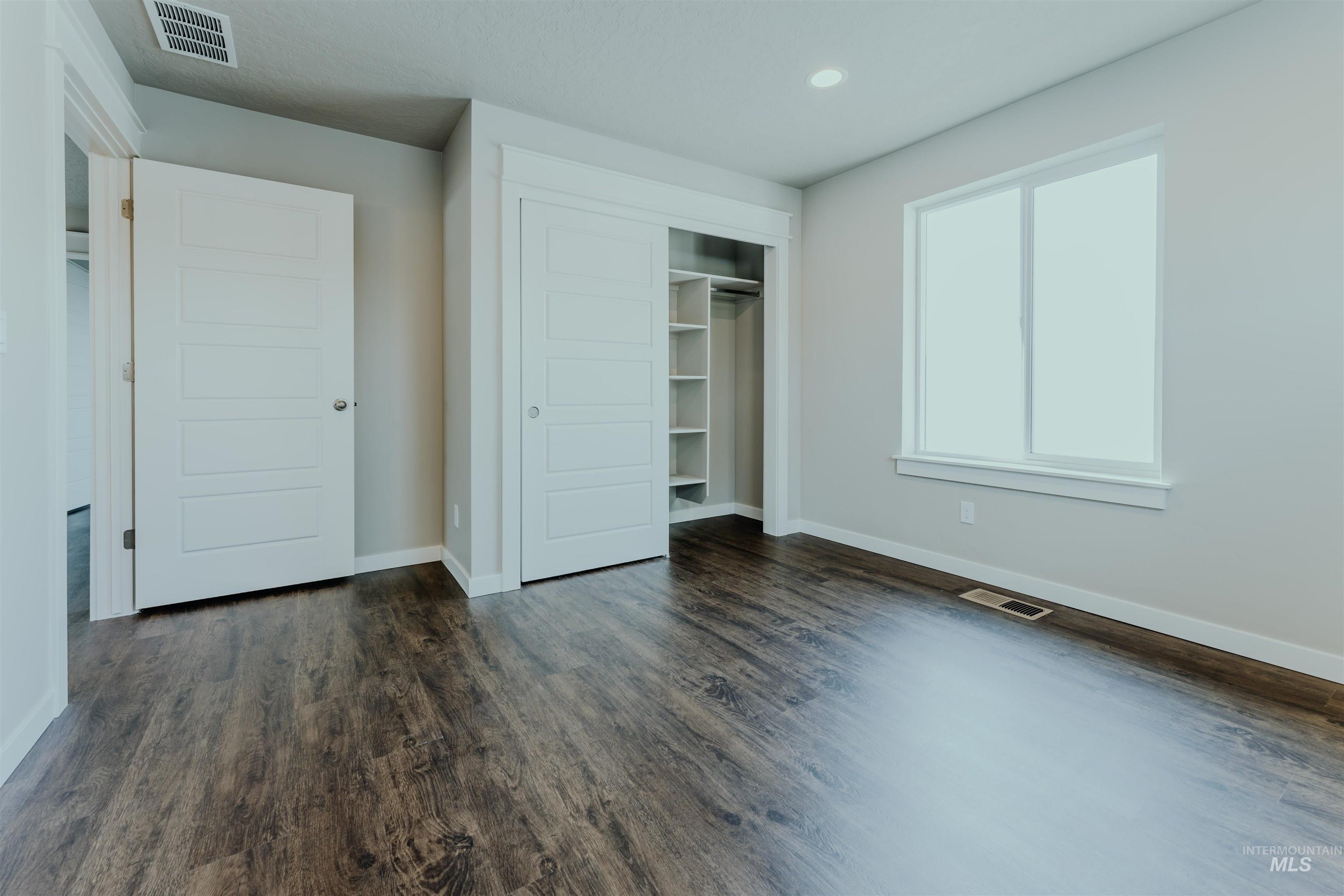 Unfurnished bedroom with a closet, dark wood-style floors, and recessed lighting
