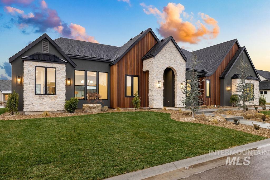 View of front of house with stone siding, a front lawn, roof with shingles, a standing seam roof, and a metal roof