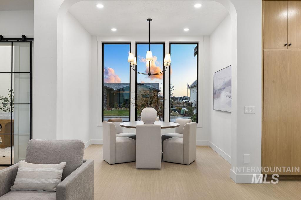 Dining area with arched walkways, a chandelier, a barn door, light wood-style flooring, and recessed lighting