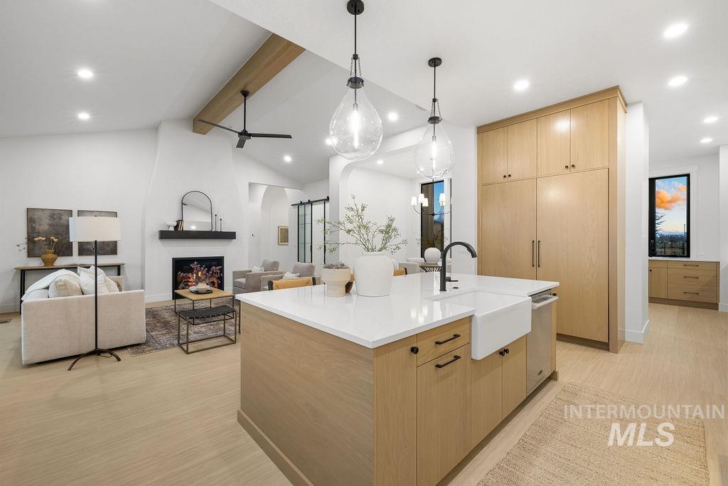 Kitchen featuring light brown cabinetry, a large fireplace, light wood-style flooring, and recessed lighting