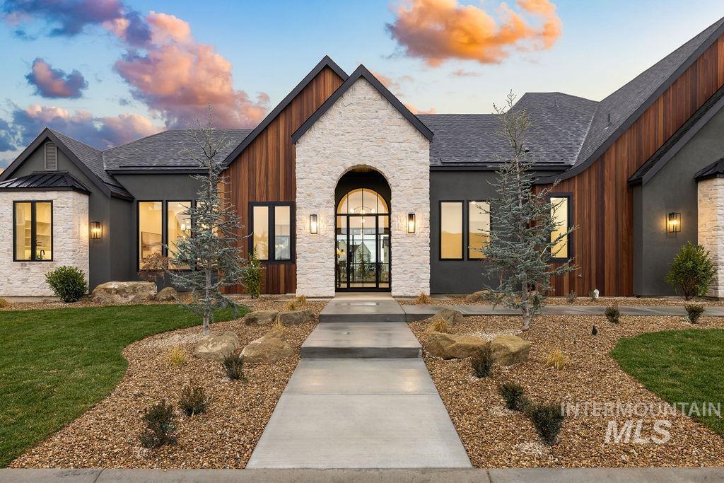 View of front of property featuring stone siding, a shingled roof, and a front yard