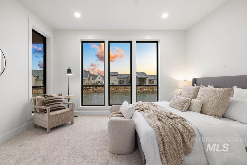 Bedroom with a water view, light colored carpet, and recessed lighting