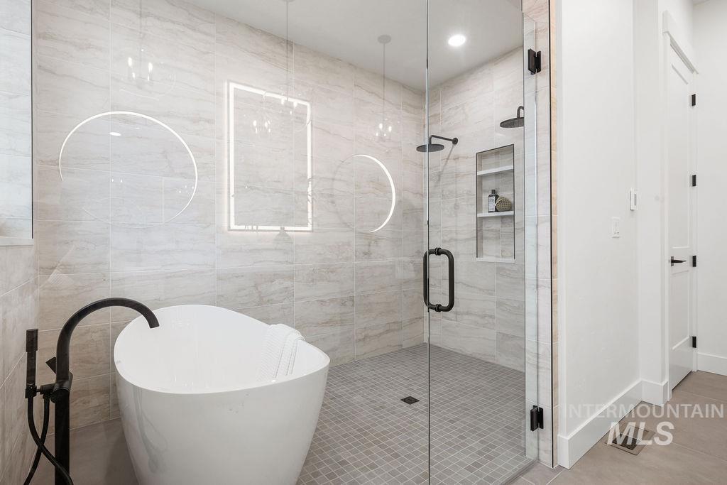 Bathroom featuring a freestanding tub, a shower stall, and tile patterned floors