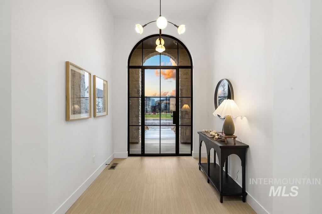 Entryway with light wood finished floors and a towering ceiling