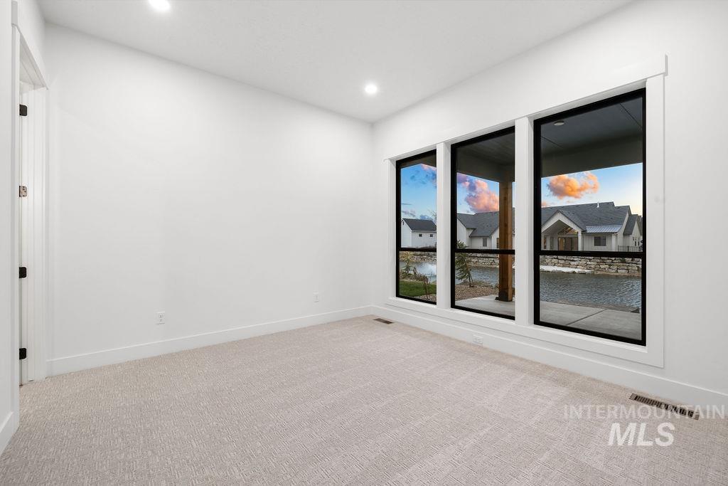 Unfurnished room with a water view, light carpet, and recessed lighting