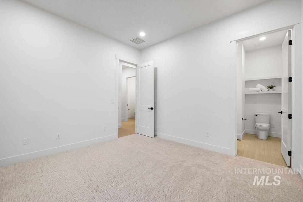 Unfurnished bedroom with ensuite bathroom, light colored carpet, and recessed lighting