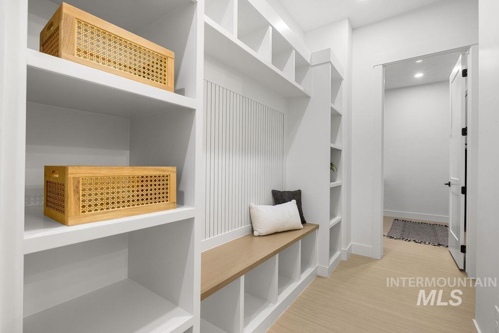 Mudroom featuring light wood finished floors, built in features, and recessed lighting