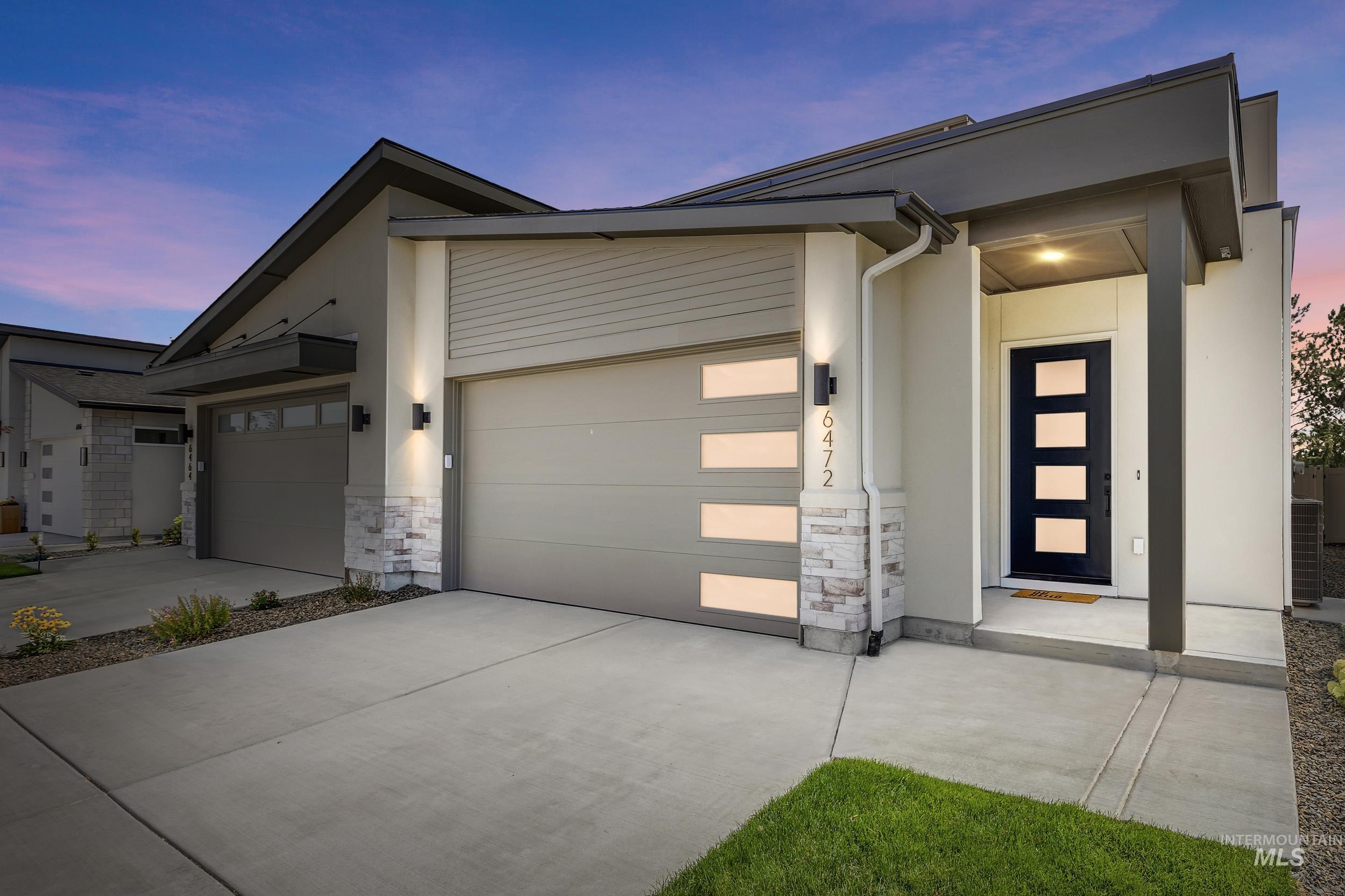 Modern home with stone siding, driveway, a garage, and stucco siding