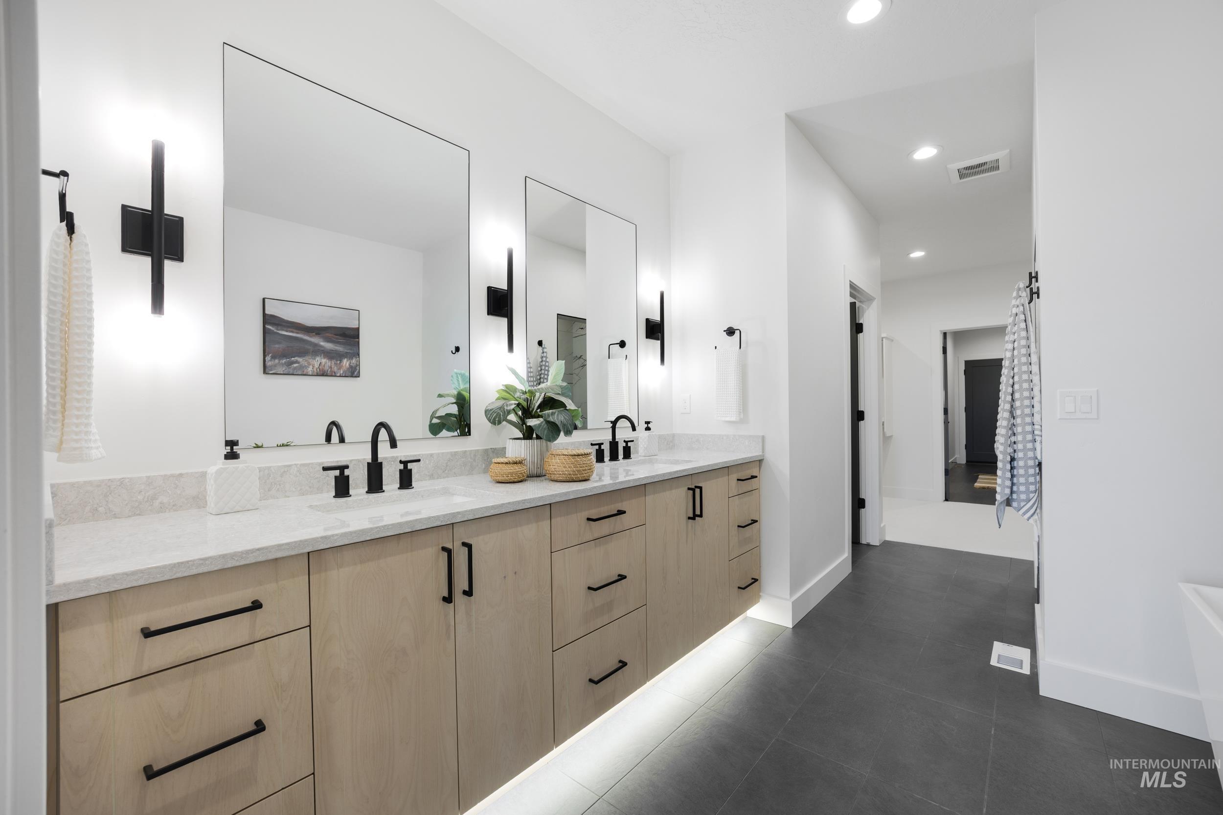 Bathroom featuring double vanity, recessed lighting, and dark tile patterned flooring