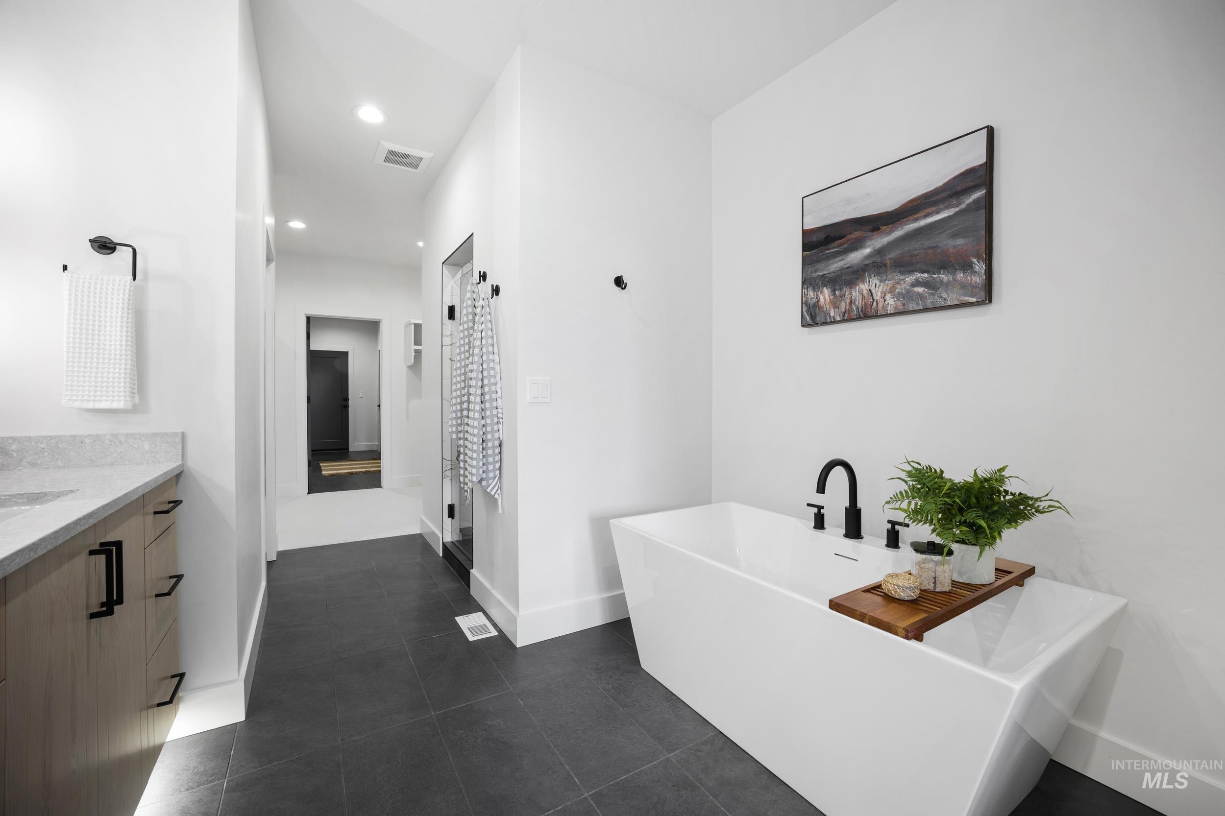 Bathroom with vanity, a freestanding bath, recessed lighting, dark tile patterned floors, and curtained shower