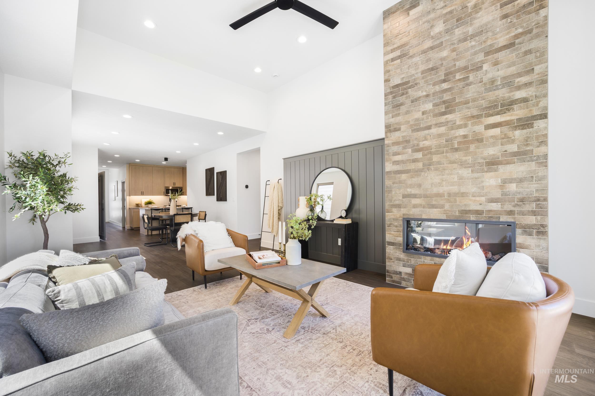 Living room featuring a multi sided fireplace, recessed lighting, a high ceiling, wood finished floors, and a ceiling fan