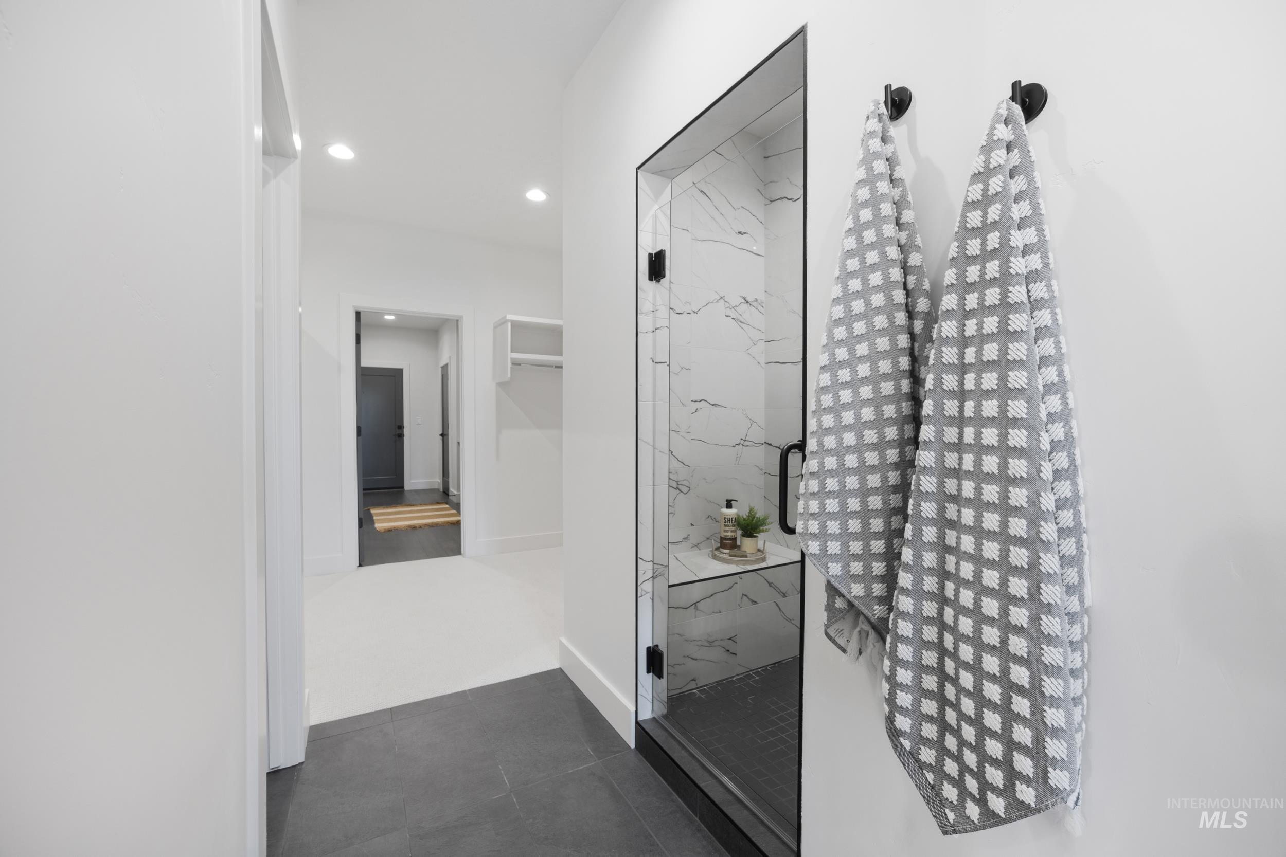 Full bath with a marble finish shower, recessed lighting, dark tile patterned floors, and a closet