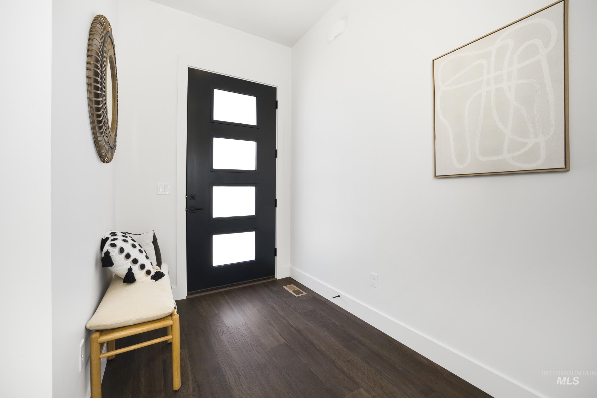 Foyer entrance with dark wood-style flooring and baseboards