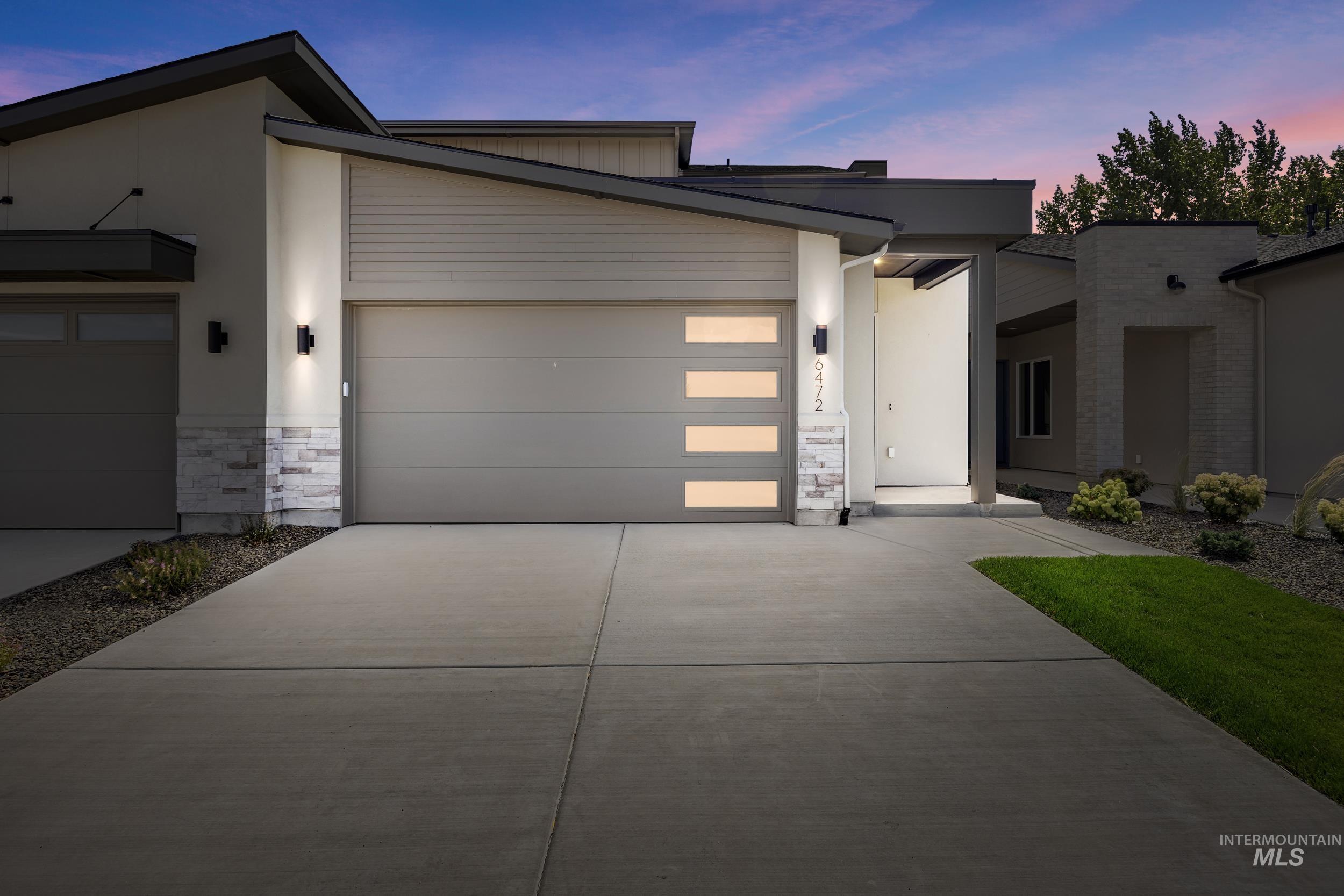 Modern home featuring stone siding, driveway, and an attached garage