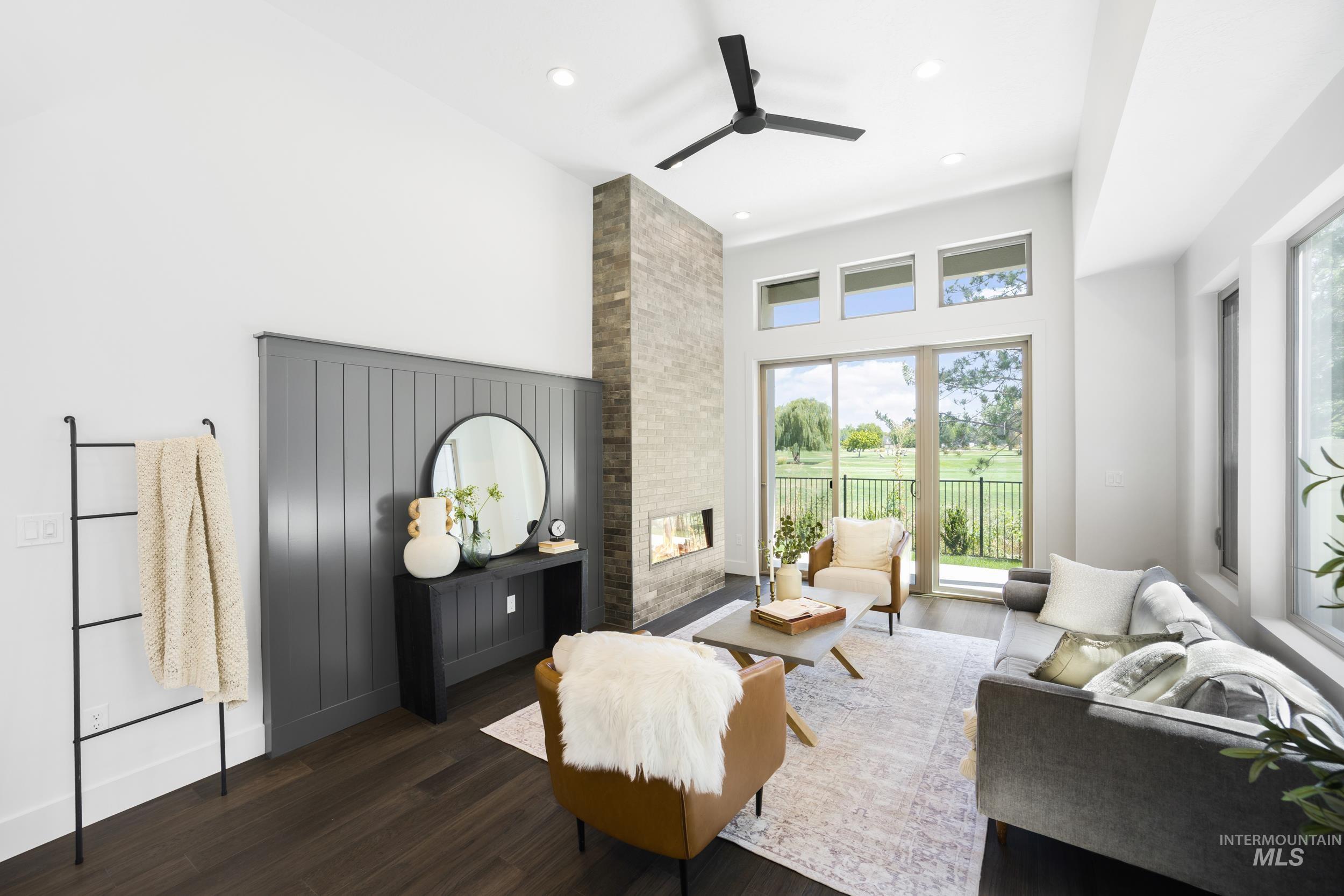 Living room featuring a fireplace, dark wood finished floors, a ceiling fan, recessed lighting, and a high ceiling