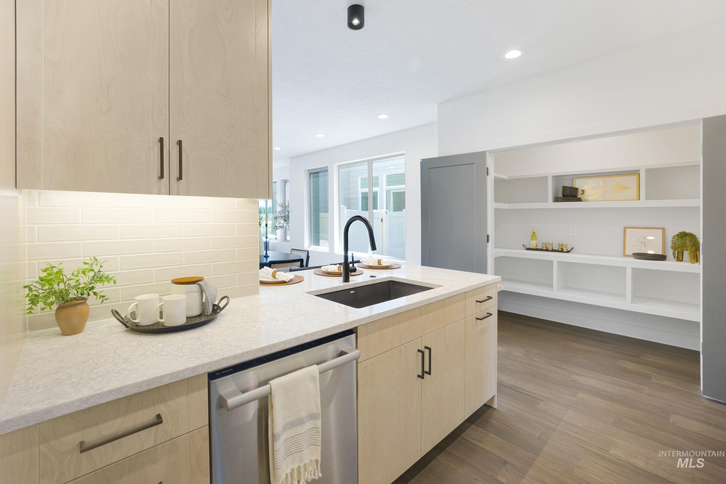 Kitchen featuring light brown cabinets, stainless steel dishwasher, light stone countertops, dark wood-style flooring, and recessed lighting