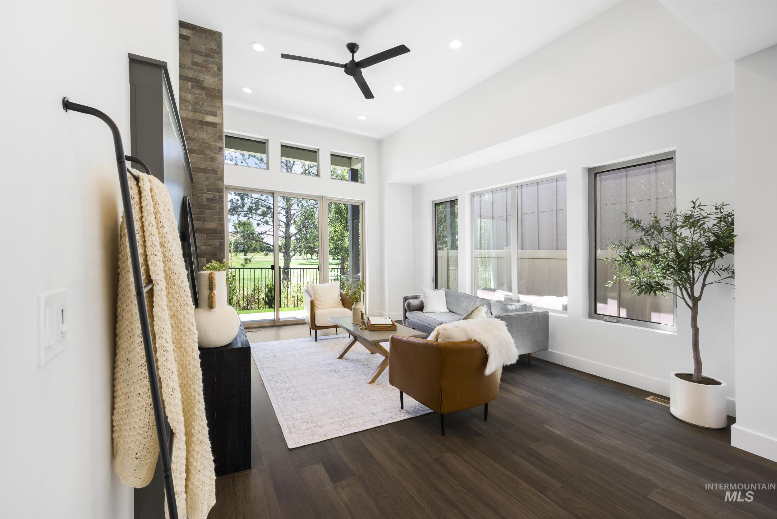 Living room featuring dark wood-type flooring, recessed lighting, ceiling fan, and a high ceiling