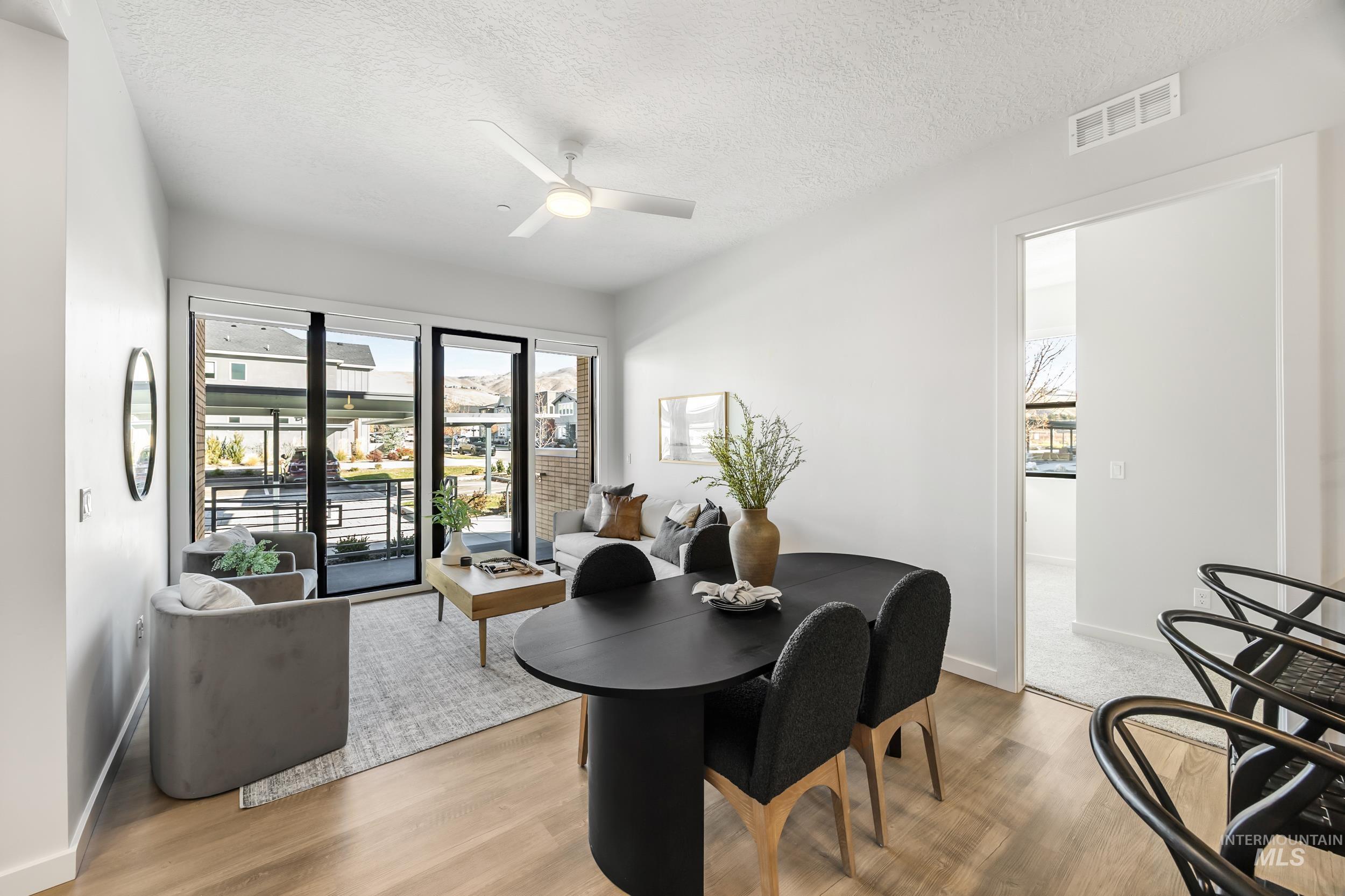 Dining area with a textured ceiling, light wood-type flooring, and ceiling fan