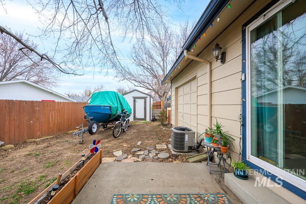 Fenced yard with a storage unit and a patio area