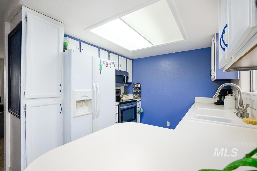 Kitchen featuring white cabinetry, appliances with stainless steel finishes, light countertops, and a peninsula