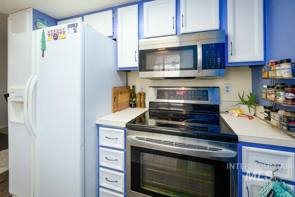 Kitchen featuring stainless steel appliances, light countertops, and white cabinetry