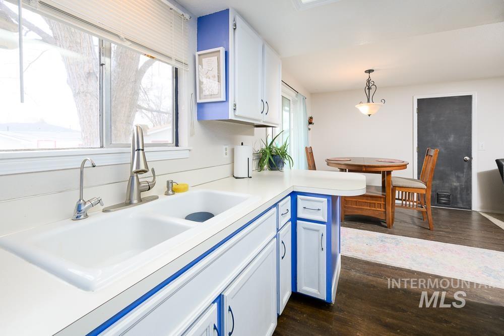 Kitchen featuring hanging light fixtures, light countertops, white cabinets, dark wood-type flooring, and blue cabinetry