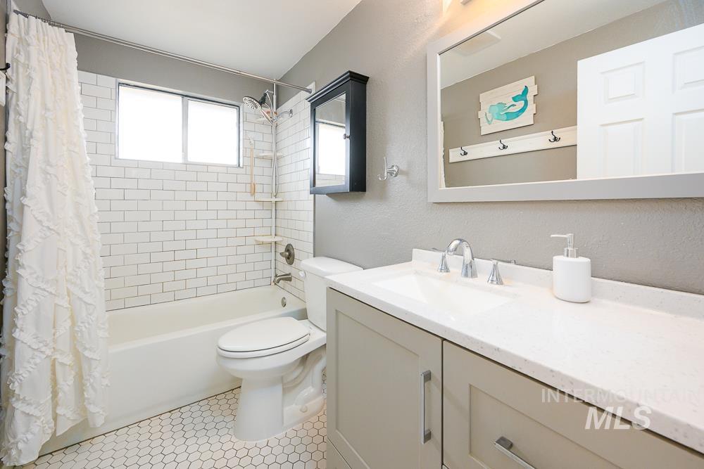 Full bath featuring shower / tub combo with curtain, vanity, a textured wall, and light tile patterned floors