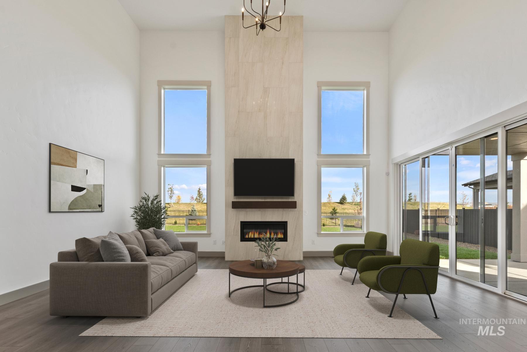 Living area featuring a towering ceiling, a tile fireplace, healthy amount of natural light, and hardwood / wood-style floors