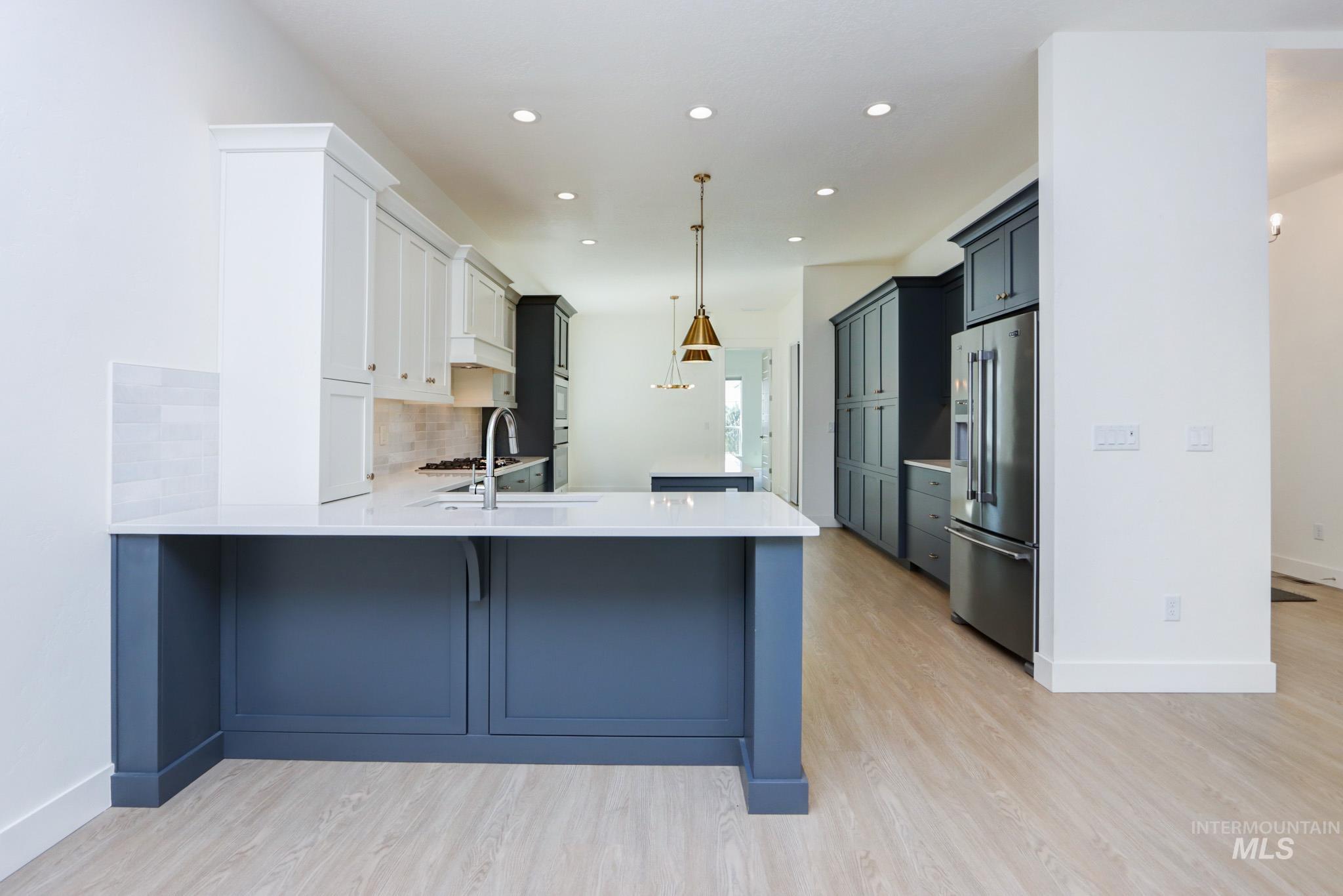 Kitchen featuring a peninsula, light countertops, tasteful backsplash, stainless steel appliances, and recessed lighting