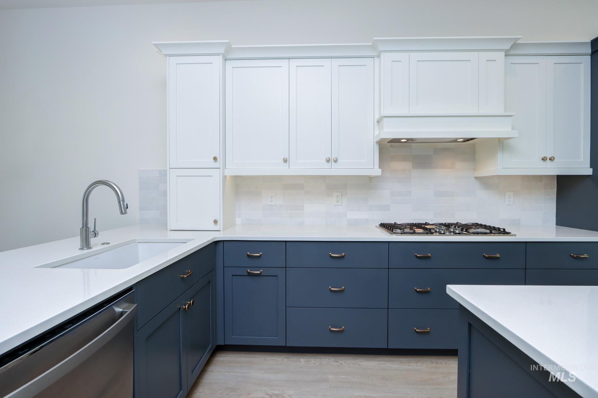 Kitchen with appliances with stainless steel finishes, white cabinetry, light countertops, and decorative backsplash
