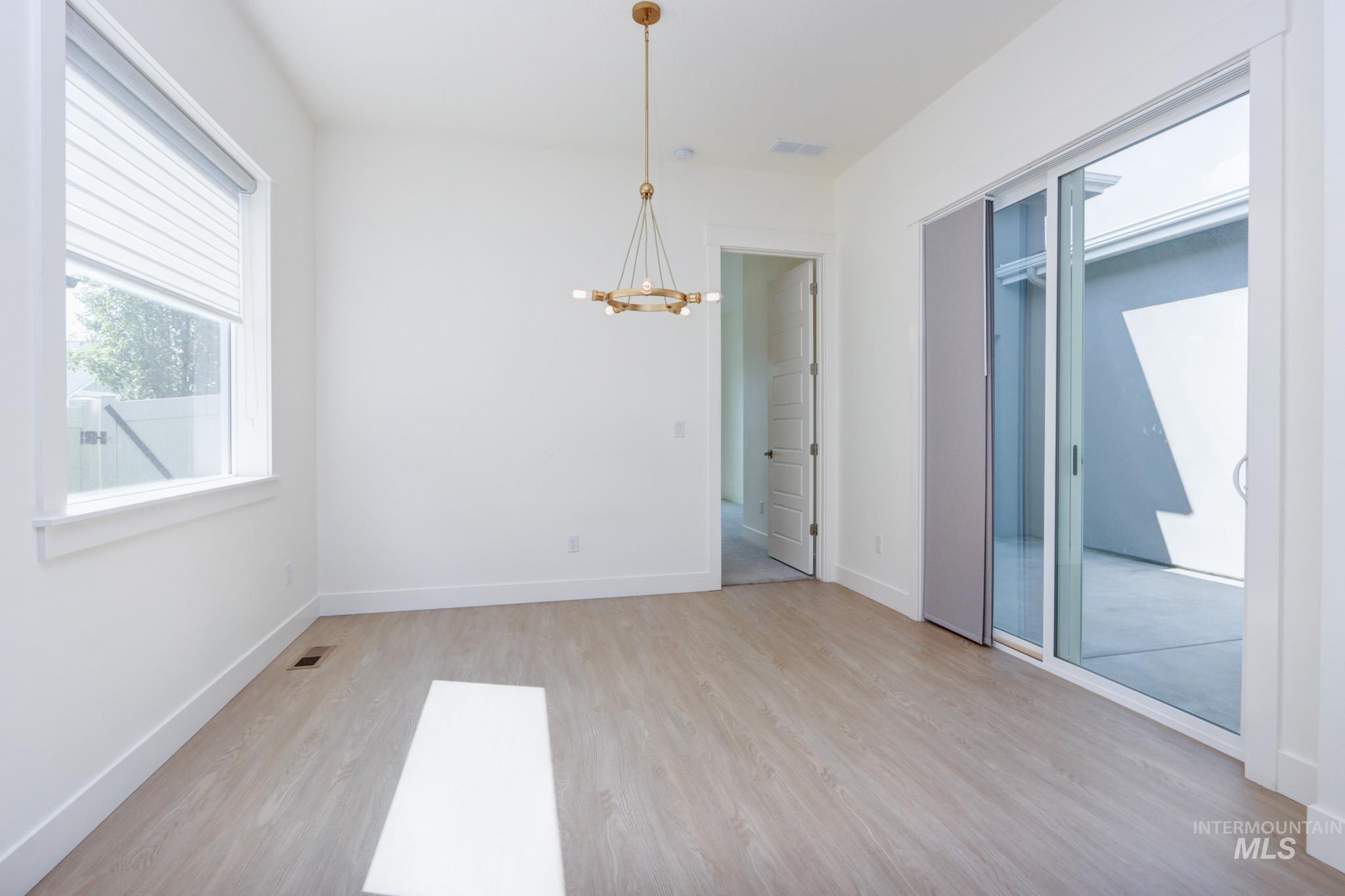 Unfurnished room featuring a chandelier and light wood-style floors