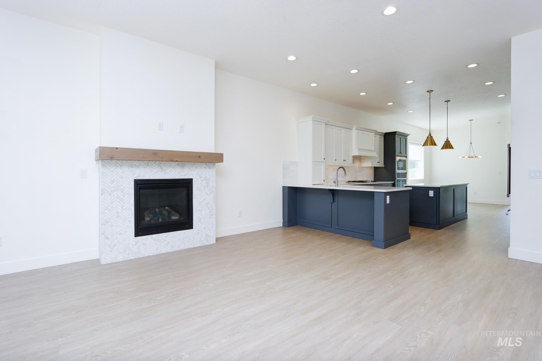 Kitchen featuring open floor plan, a kitchen bar, light wood-style floors, a peninsula, and light countertops