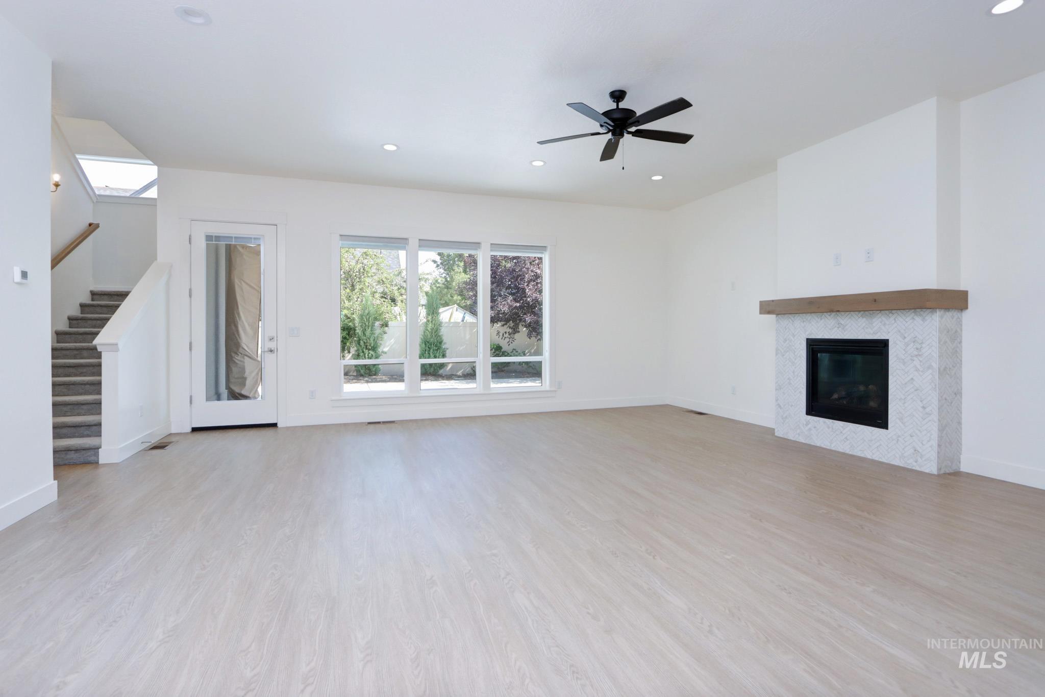 Unfurnished living room featuring plenty of natural light, light wood-style floors, recessed lighting, stairway, and a tile fireplace