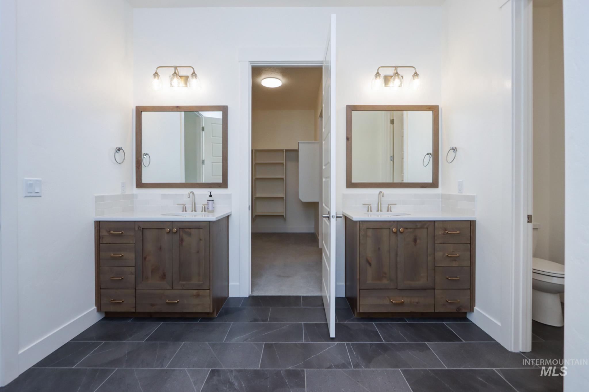 Full bathroom featuring two vanities, tile patterned floors, and a closet