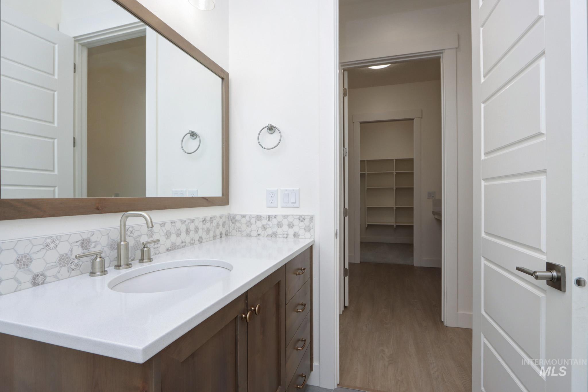 Bathroom with vanity, wood finished floors, and backsplash