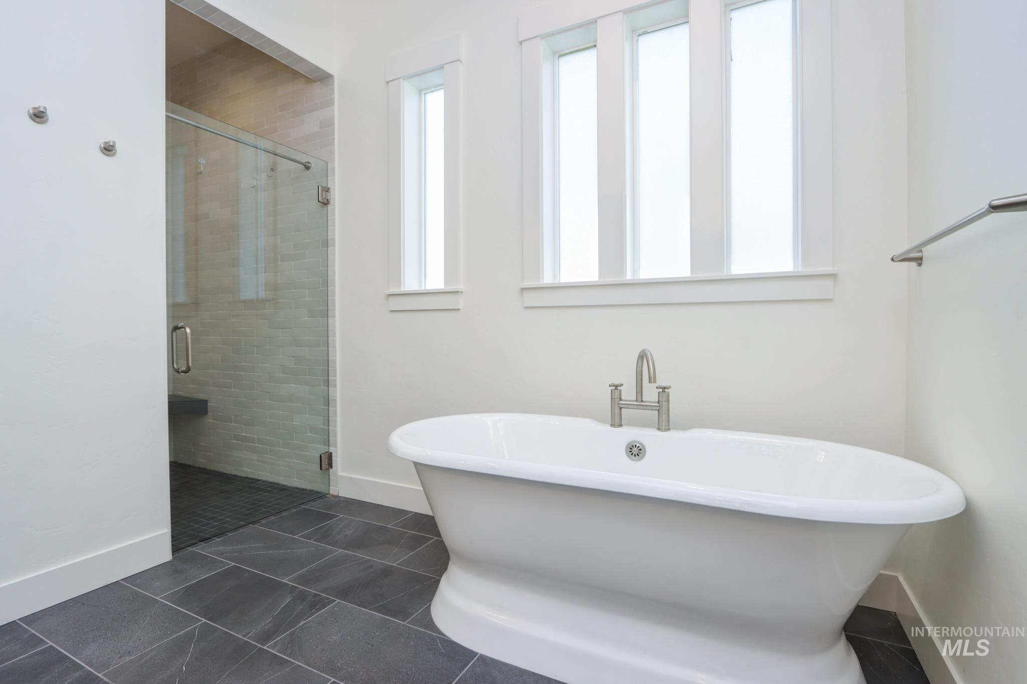 Bathroom with a freestanding bath, a shower stall, and tile patterned flooring