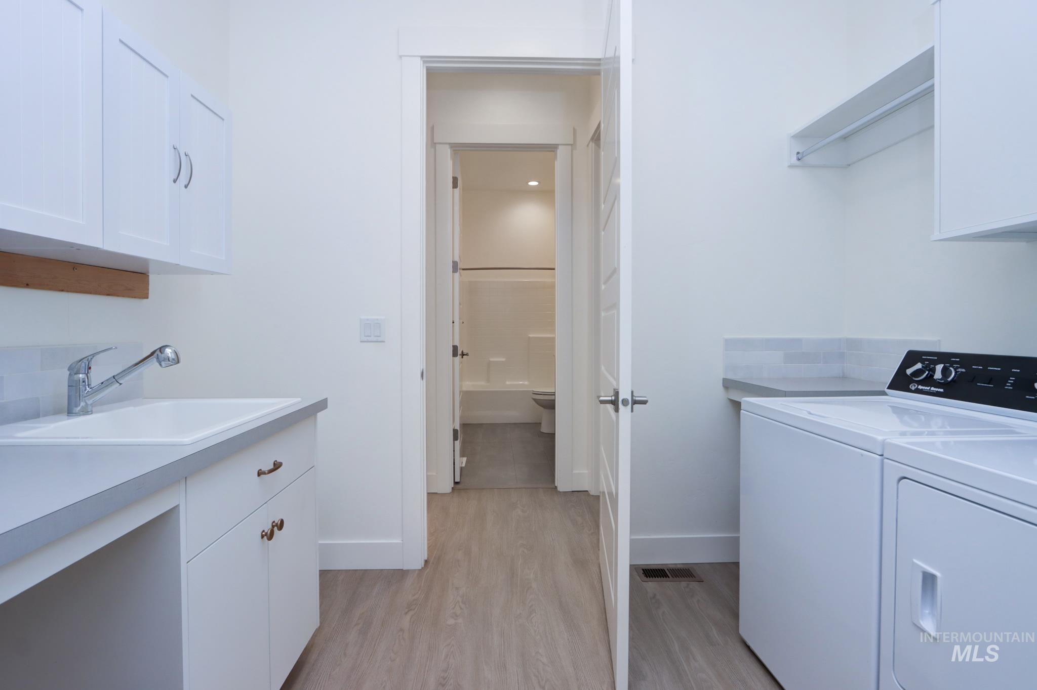 Washroom featuring cabinet space, washing machine and dryer, and light wood-type flooring