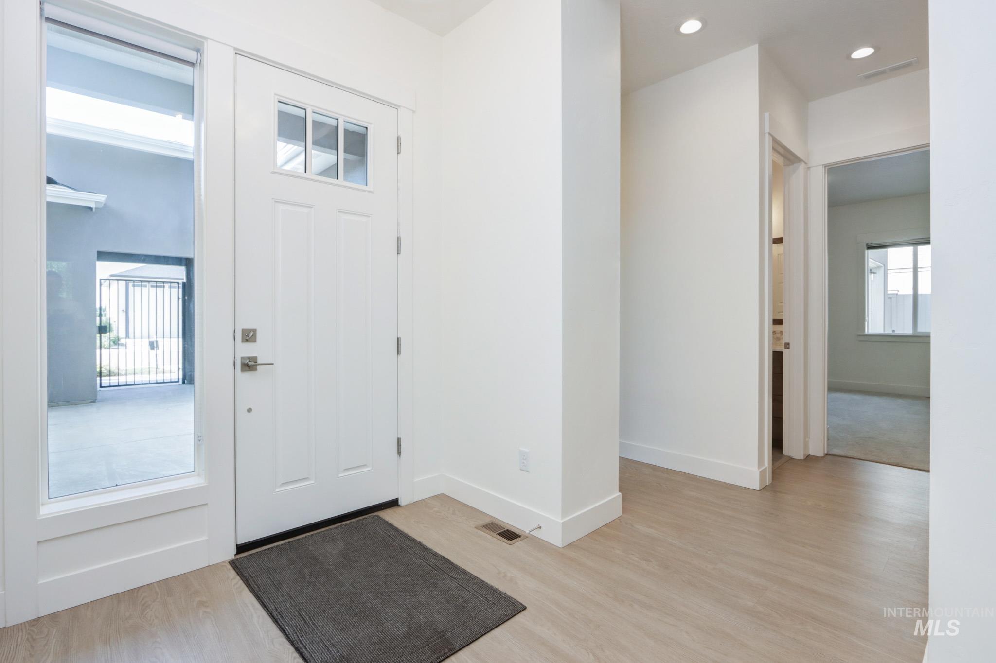 Entrance foyer with light wood-style flooring and recessed lighting