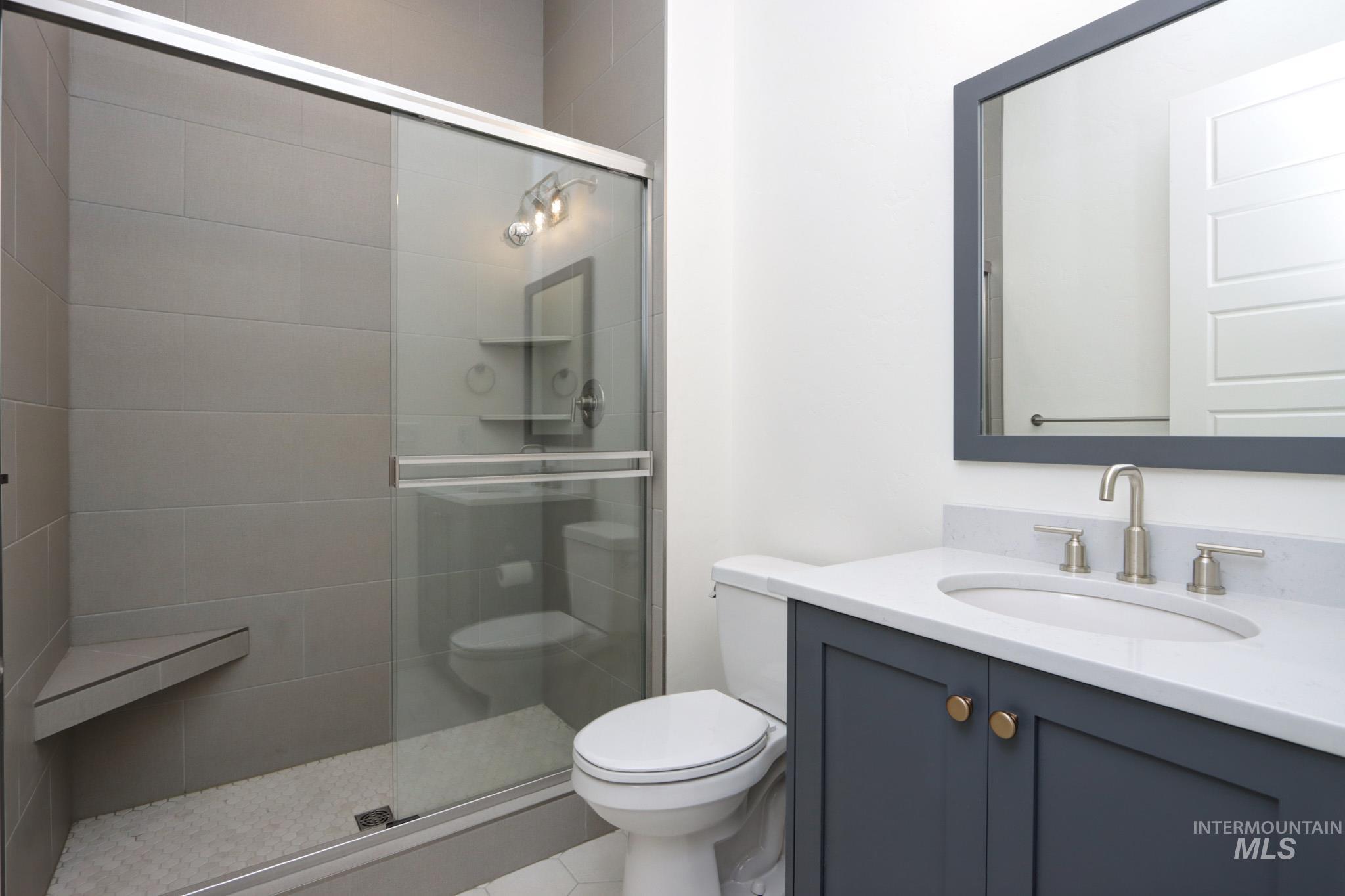 Bathroom featuring a stall shower, vanity, and tile patterned flooring