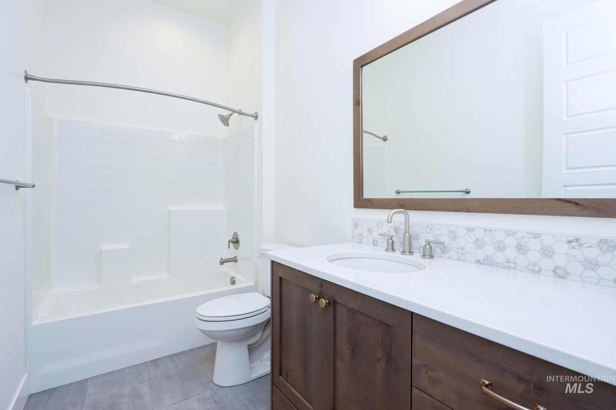 Full bathroom with vanity, shower / bathtub combination, tile patterned flooring, and tasteful backsplash