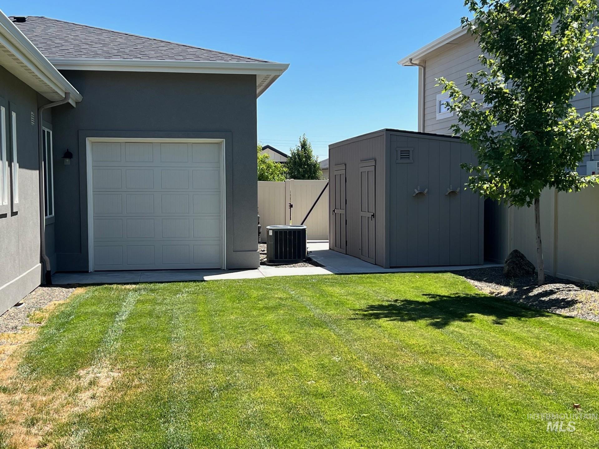 View of yard featuring a storage unit, a garage, and driveway