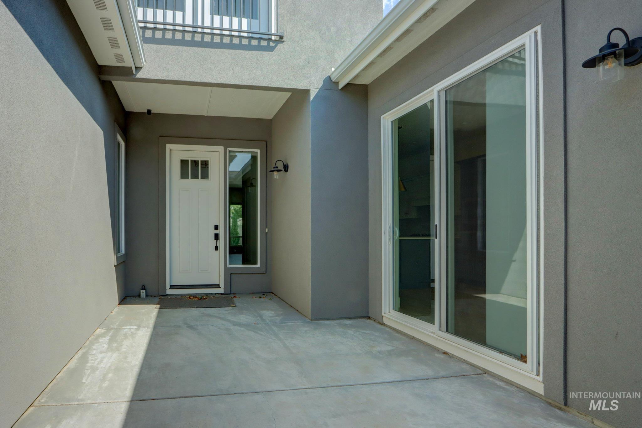 View of exterior entry with a patio and stucco siding