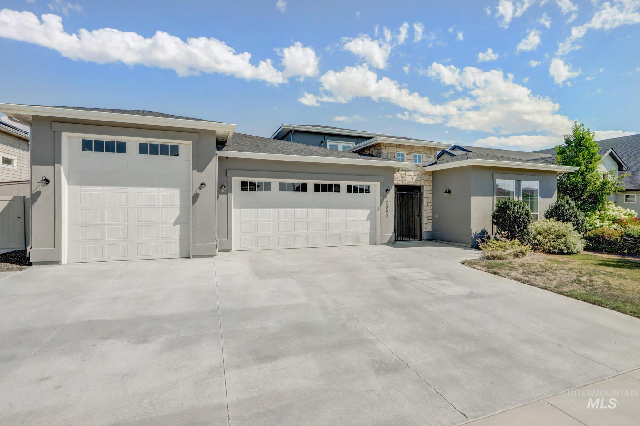Prairie-style home featuring stucco siding, a garage, stone siding, and concrete driveway